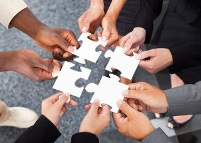 Diverse group of hands holding puzzle pieces together